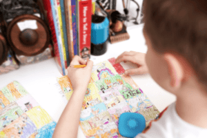 Closeup image of child drawing a comic with crayons on a desk