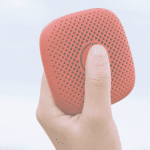 Child's hand holding brick-colored Relay in the air with thumb depressing talk button