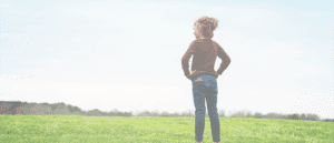 Girl standing with hands on hips overlooking a field with a Relay in her back pocket