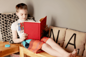 Reading nook: Child reading book on a wooden bench in a corner