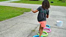 Young girl running through toy hoops in the drive-way.