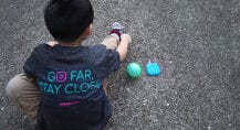 Young boy sitting on the ground next to a tennis ball and Relay device.