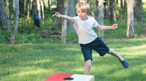 Young boy playing cornhole and preparing to throw his beanbag