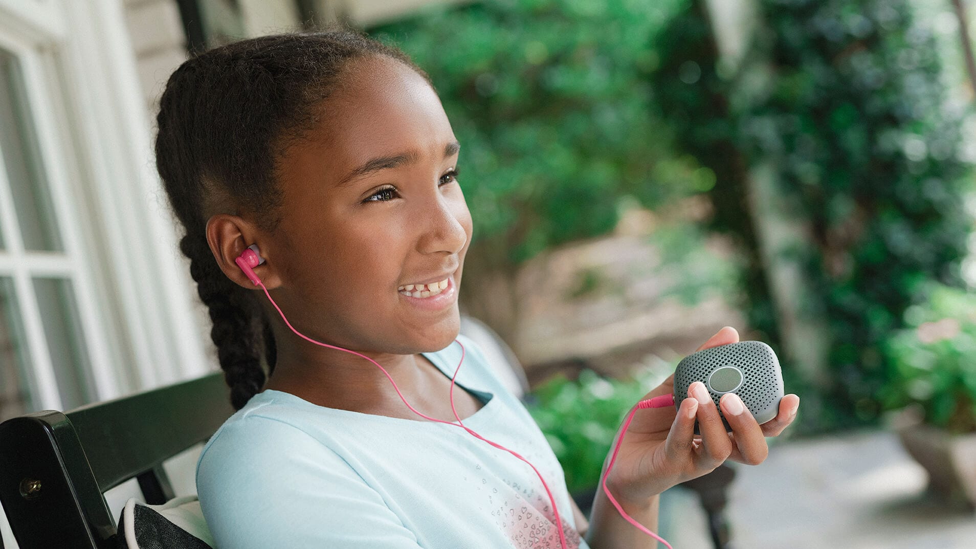 girl smiling while listening to music. Her earbuds are plugged into her Relay