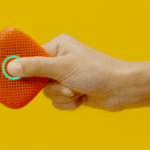 hand holds a brick red Relay in the air against a yellow background
